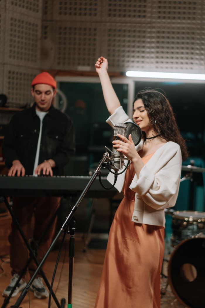 gallery-2 Energetic woman singing with keyboard accompaniment in a music studio.